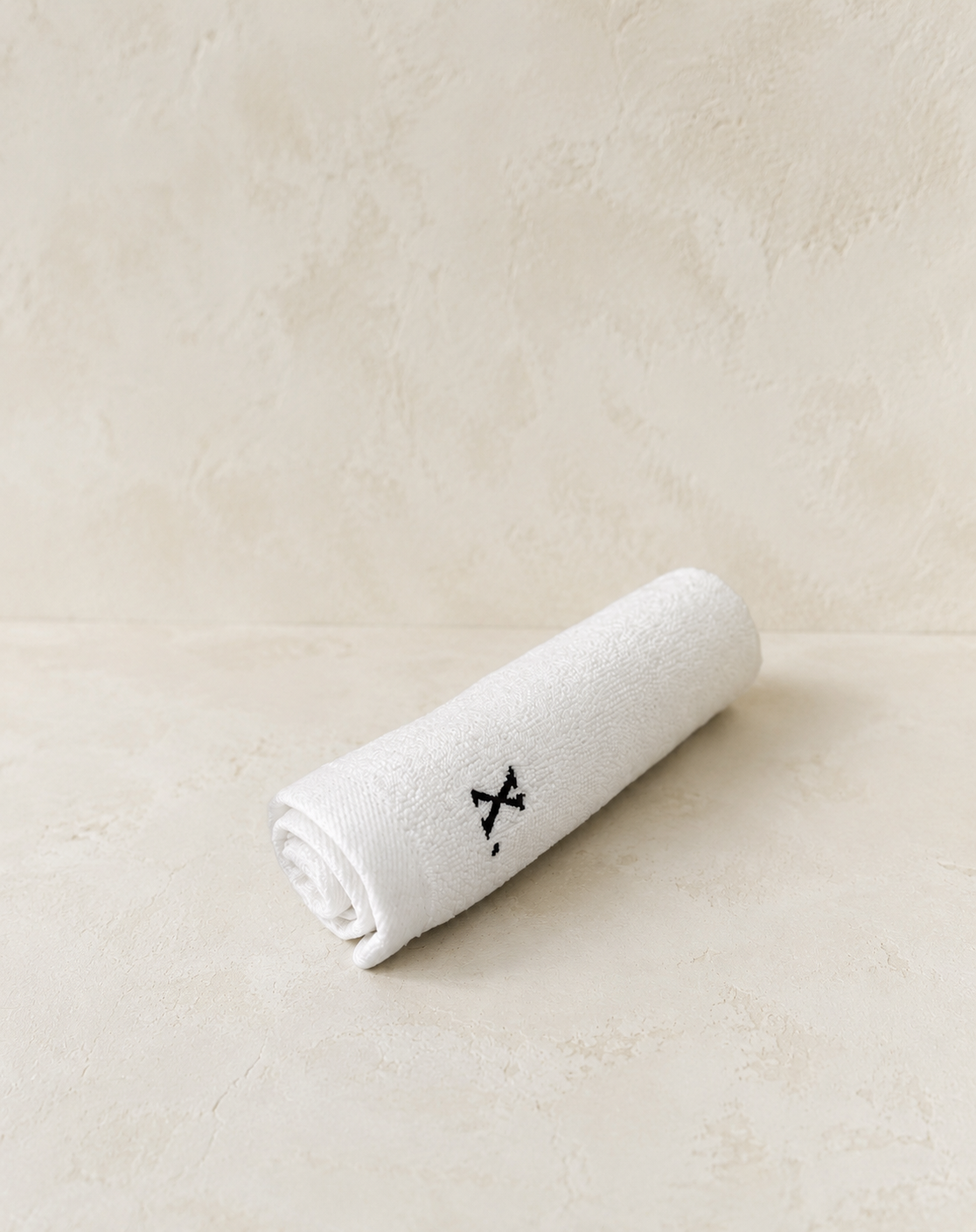 Luxe Co. embroidered service towel on a textured stone surface